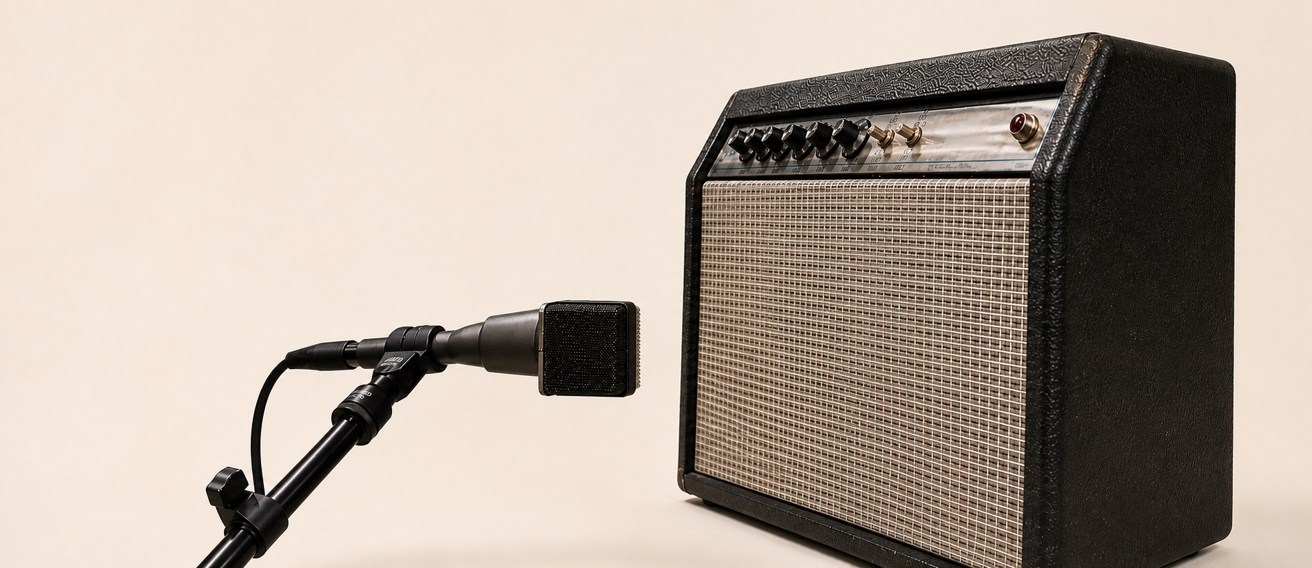 A valve combo amplifier on a plain warm ground, with a studio microphone on a stand set close to its grille cloth.